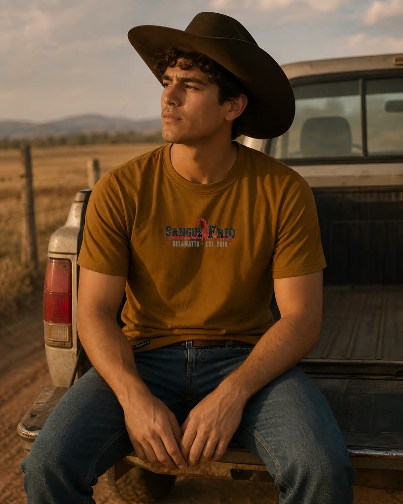 Homem de chapéu vestindo a camiseta caramelo Sangue Frio na caçamba da caminhonete