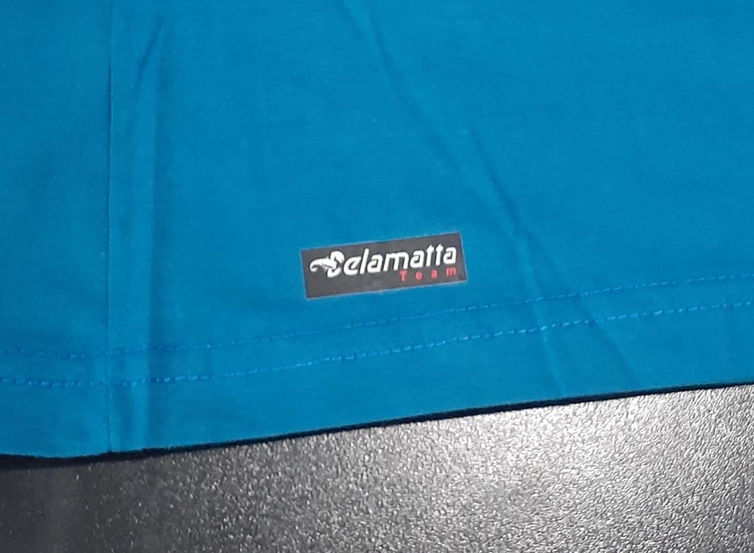 Etiqueta bordada Delamatta Team costurada na barra da camiseta